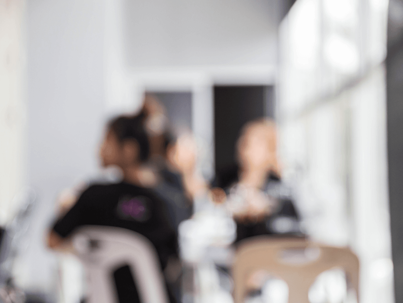 Soft focus of Simon Warwick Salon team in discussion near the Maida Vale salon window, reflecting a calm and professional environment.